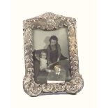 Edwardian silver mounted shaped rectangular photograph frame with embossed cherub mask, scroll and