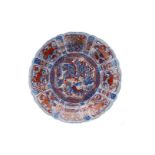 A blue and overglaze red porcelain deep charger with scalloped rim, decorated with flowers, fruits