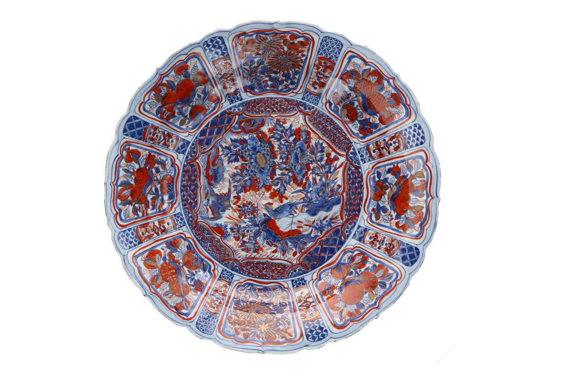 A blue and overglaze red porcelain deep charger with scalloped rim, decorated with flowers, fruits