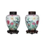 A pair of polychrome porcelain vases with a wooden lid and a lotus flower-shaped base, decorated