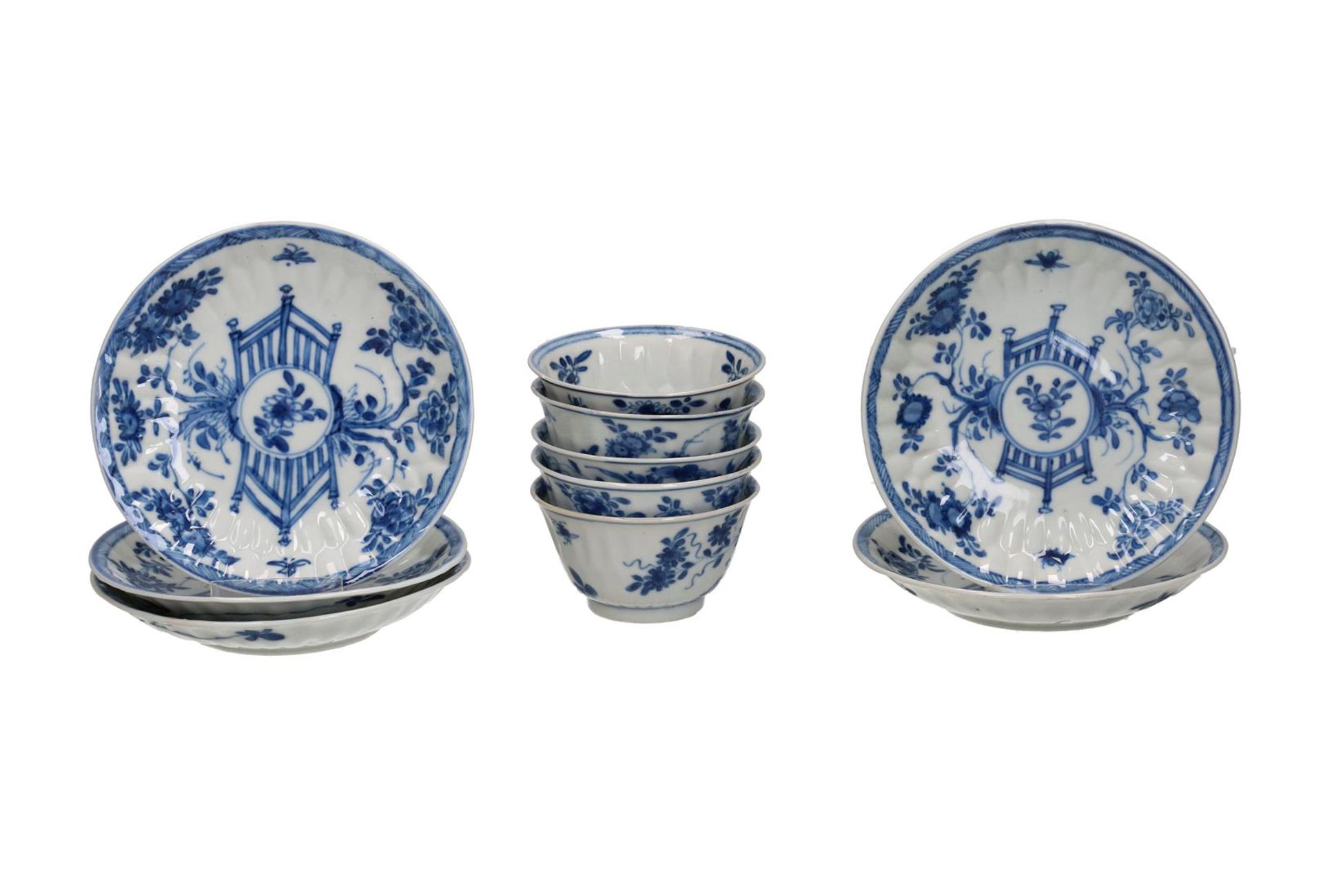 A set of six blue and white porcelain cups and saucers, decorated with a floral decor and a fence in