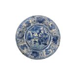 A blue and white porcelain deep charger, decorated with reserves depicting flowers, antiquities
