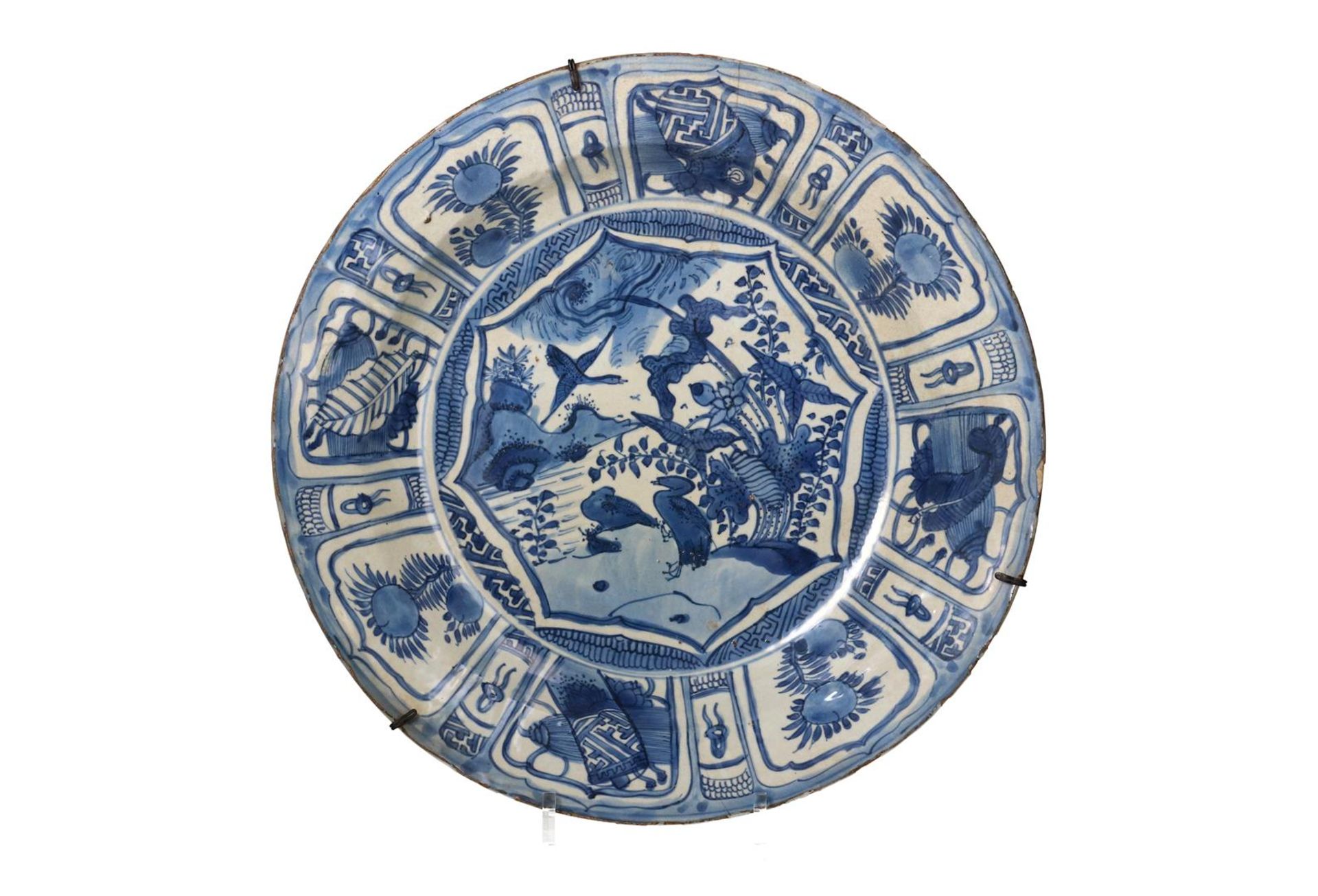 A blue and white porcelain deep charger, decorated with reserves depicting flowers, antiquities