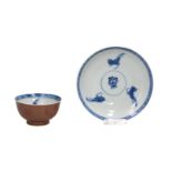 A blue and white porcelain cup and saucer, the reverse covered in capuchin glaze, decorated with a