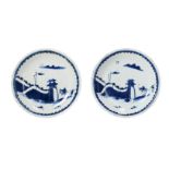 A pair of blue and white porcelain saucers, decorated with two figures on horseback approaching a