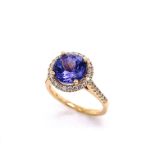 A CLASSIC HALO DESIGN TANZANITE AND DIAMOND RING