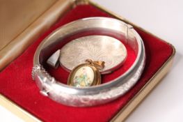 A silver bangle hallmarked Chester 1952, together with a silver locket and costume portrait pendant