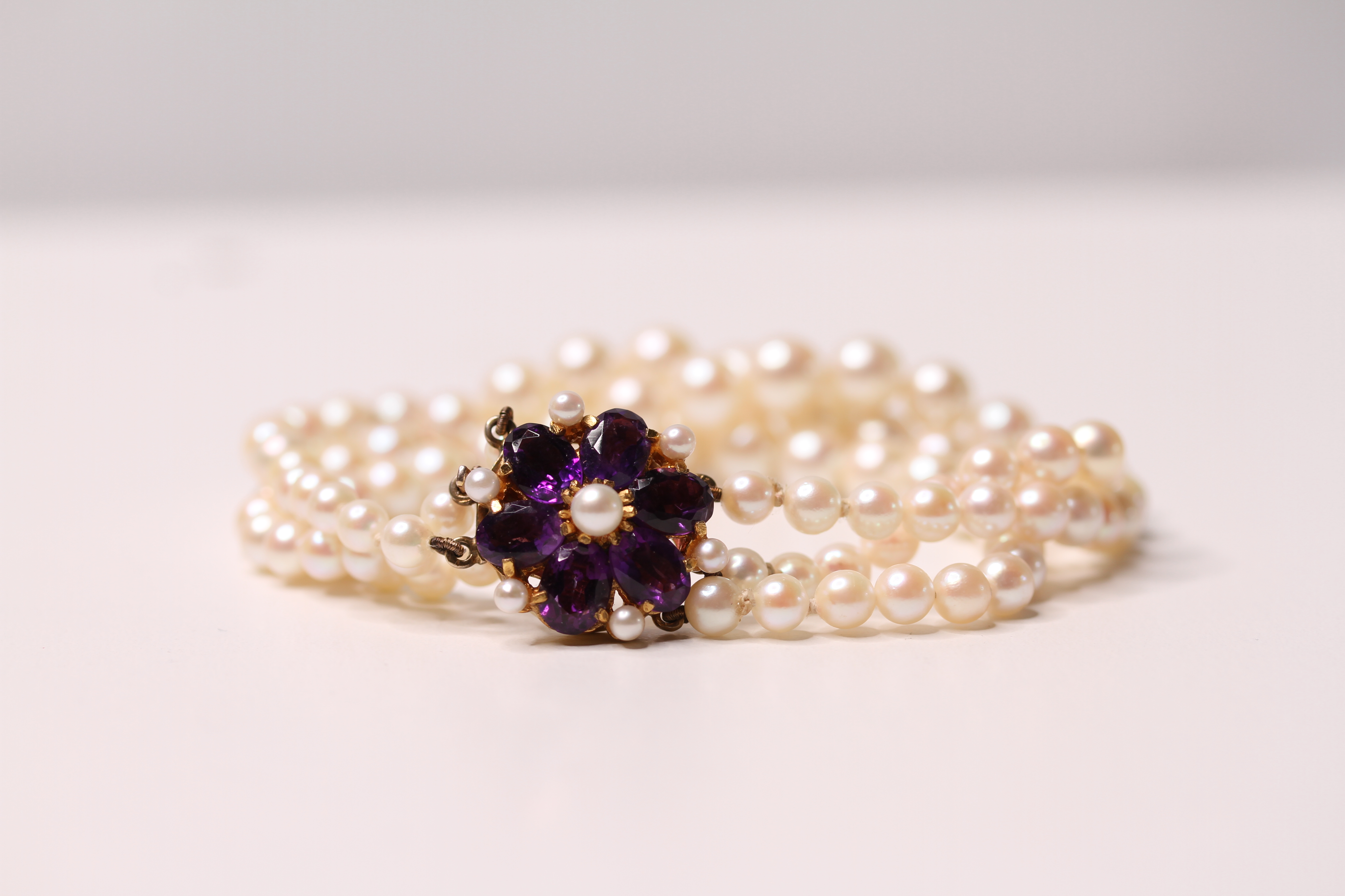*TO BE SOLD WITHOUT RESERVE*A yellow-metal, pearl and amethyst bracelet, comprising three strands of