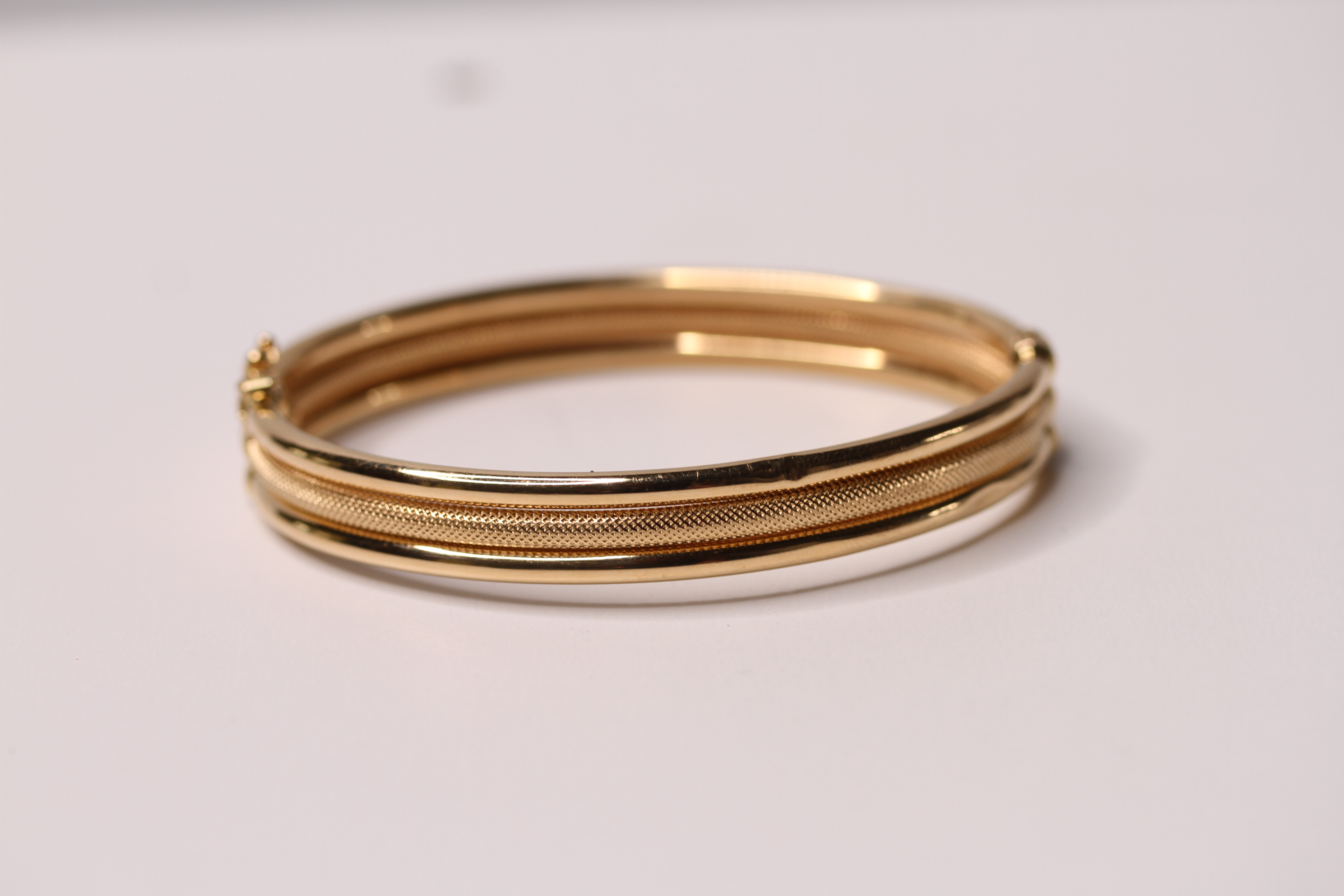 *TO BE SOLD WITHOUT RESERVE*An 18ct gold bangle made up of three bands, one with a textured