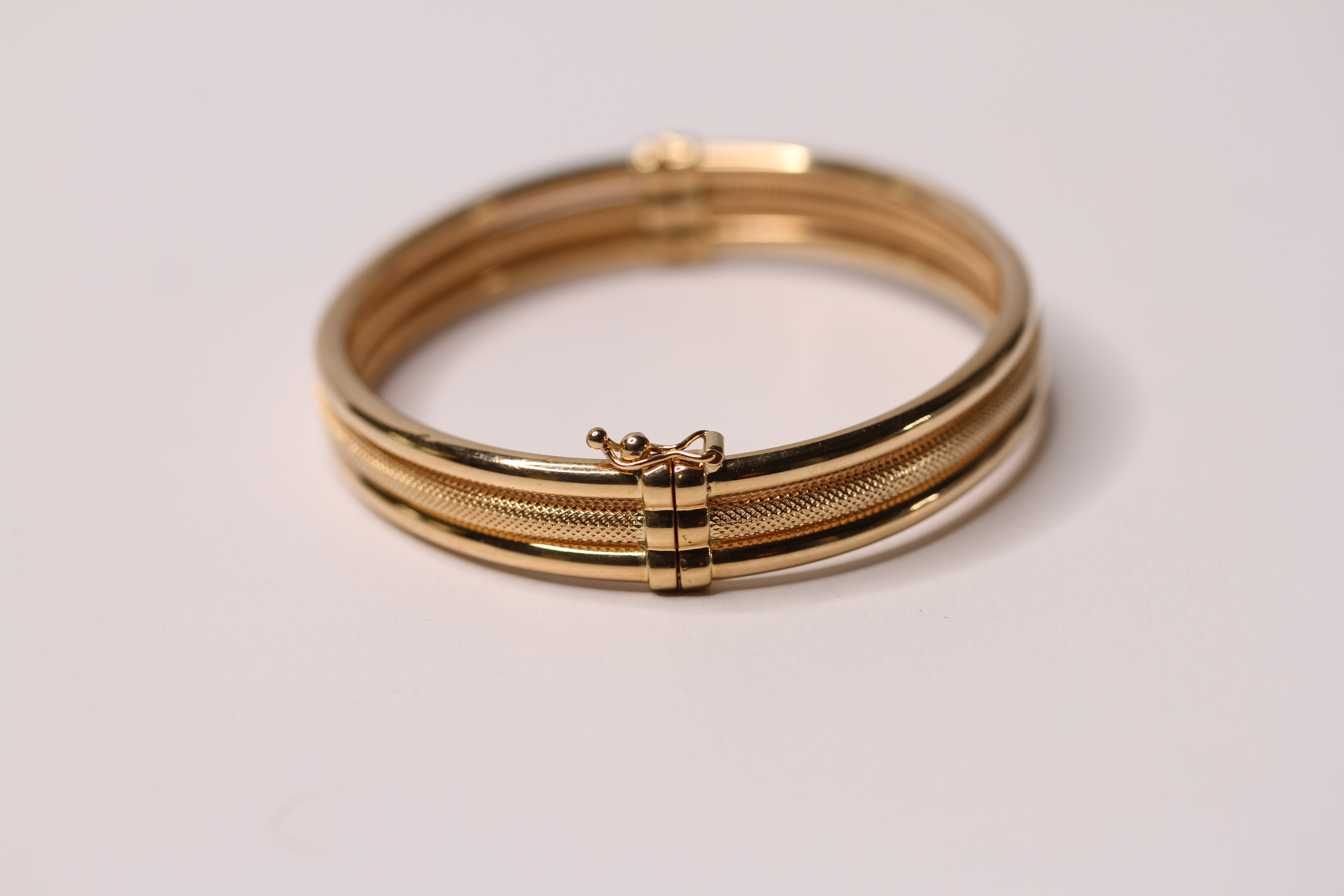 *TO BE SOLD WITHOUT RESERVE*An 18ct gold bangle made up of three bands, one with a textured - Image 2 of 2