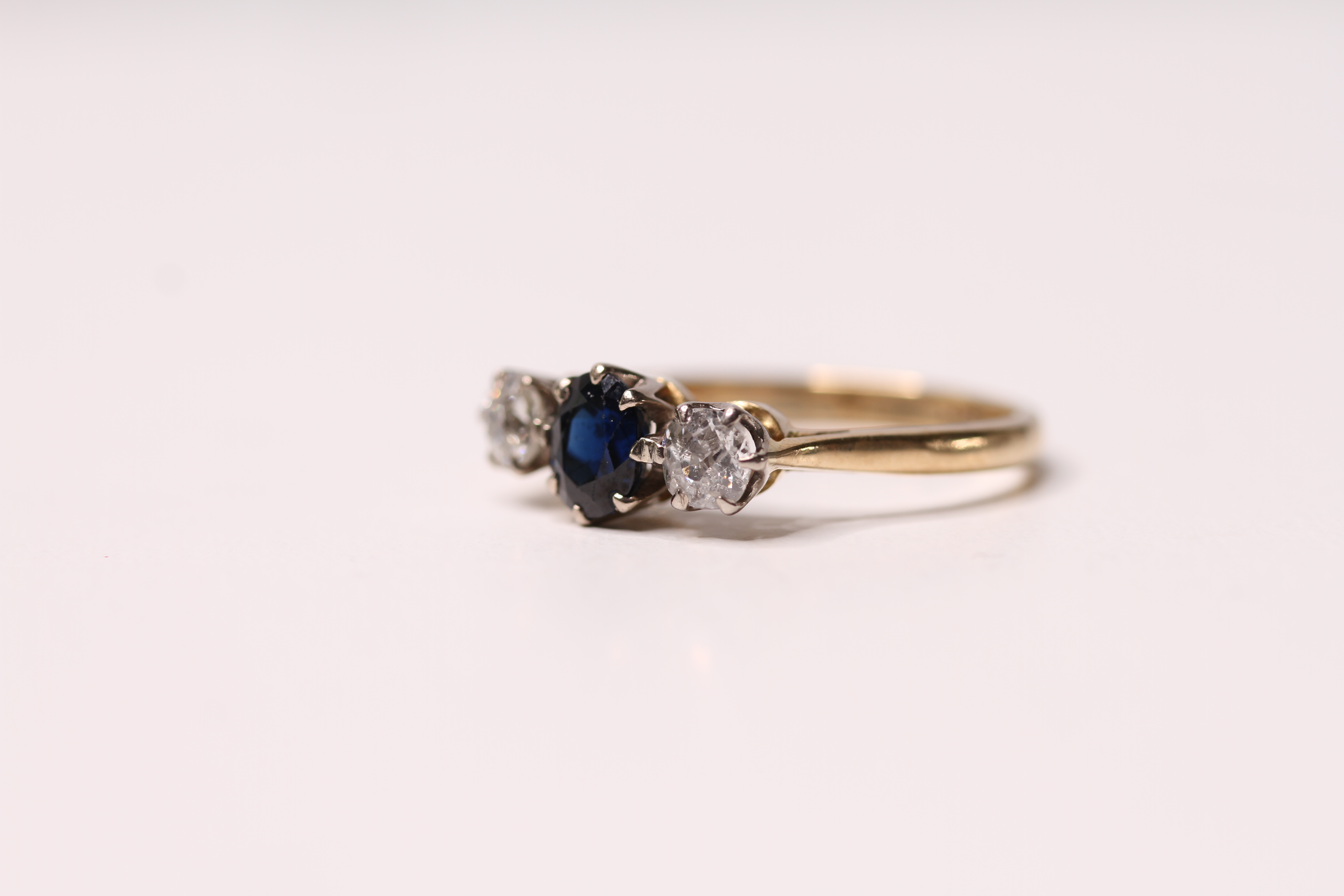 *TO BE SOLD WITHOUT RESERVE*An 18 carat gold ring set with a blue sapphire flanked by old cut