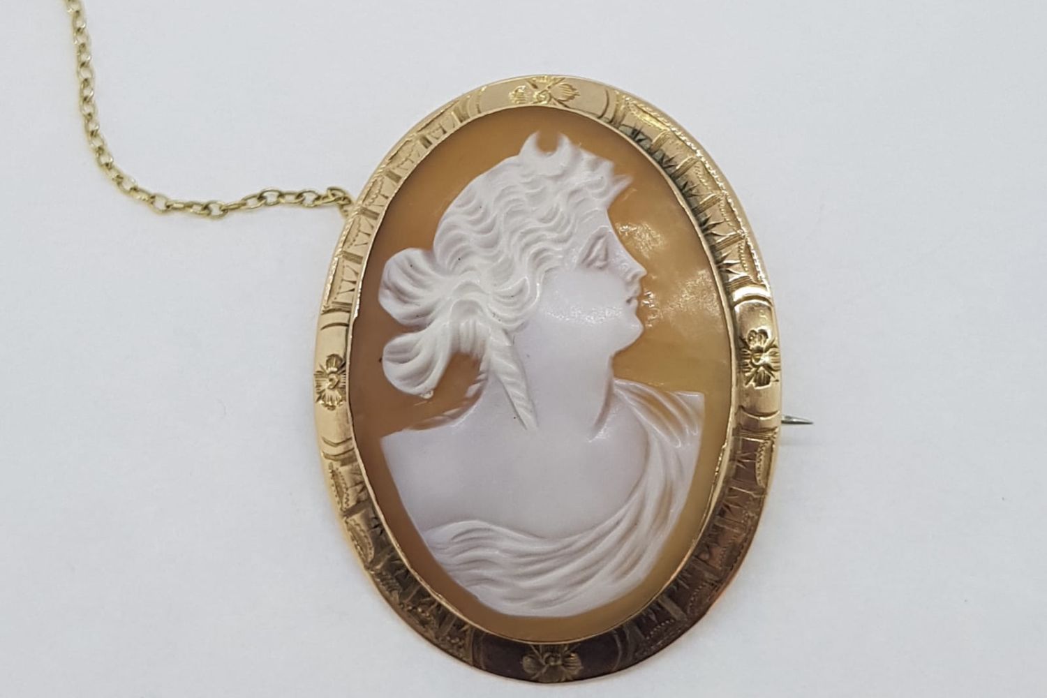 Detailed Gold Rimmed Cameo, marked 9ct yellow gold, with a single pin and safety chain,
