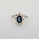 18 carat white gold oval sapphire and round brilliant cut diamond cluster ring. Approximate sapphire