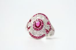 Ornate platinum ruby and diamond dress ring. Set with an oval-cut ruby, calibre-cut rubies and RBC