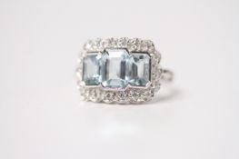 18ct white gold 3-stone aquamarine and diamond cluster dress ring. Emerald-cut aquamarines 2.10ct.