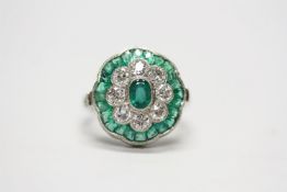 Platinum emerald and diamond floral-style dress ring. Set with a central oval-cut emerald, an