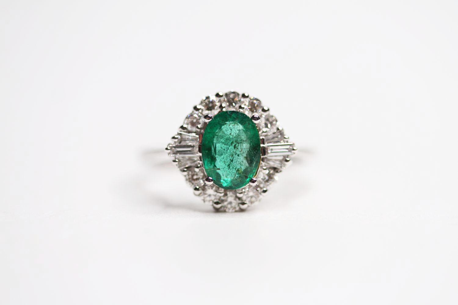 18ct white gold oval emerald and diamond cluster ring. Emerald 1.20ct. RBC and tapered baguette