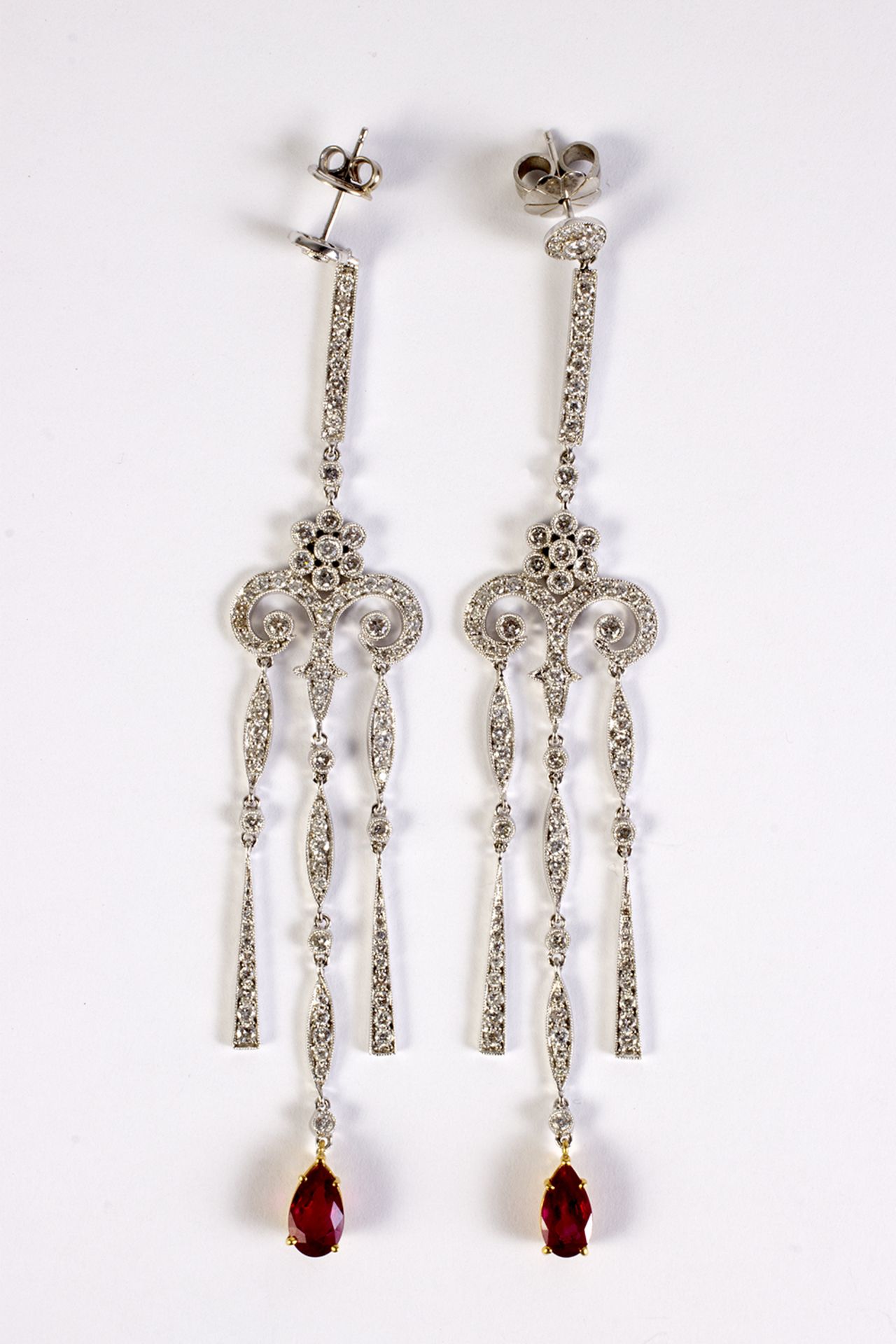 Pendientes largos en oro blanco, diamantes talla brillante y rubí talla perilla.