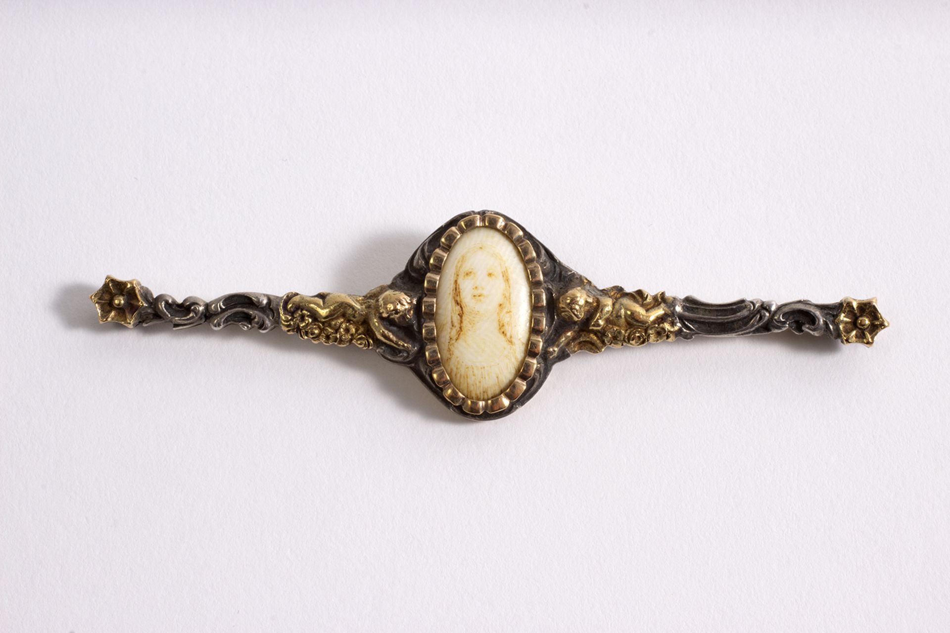 Broche lanzadera estilo noucentista en plata y oro con busto femenino pintado sobre marfilina.