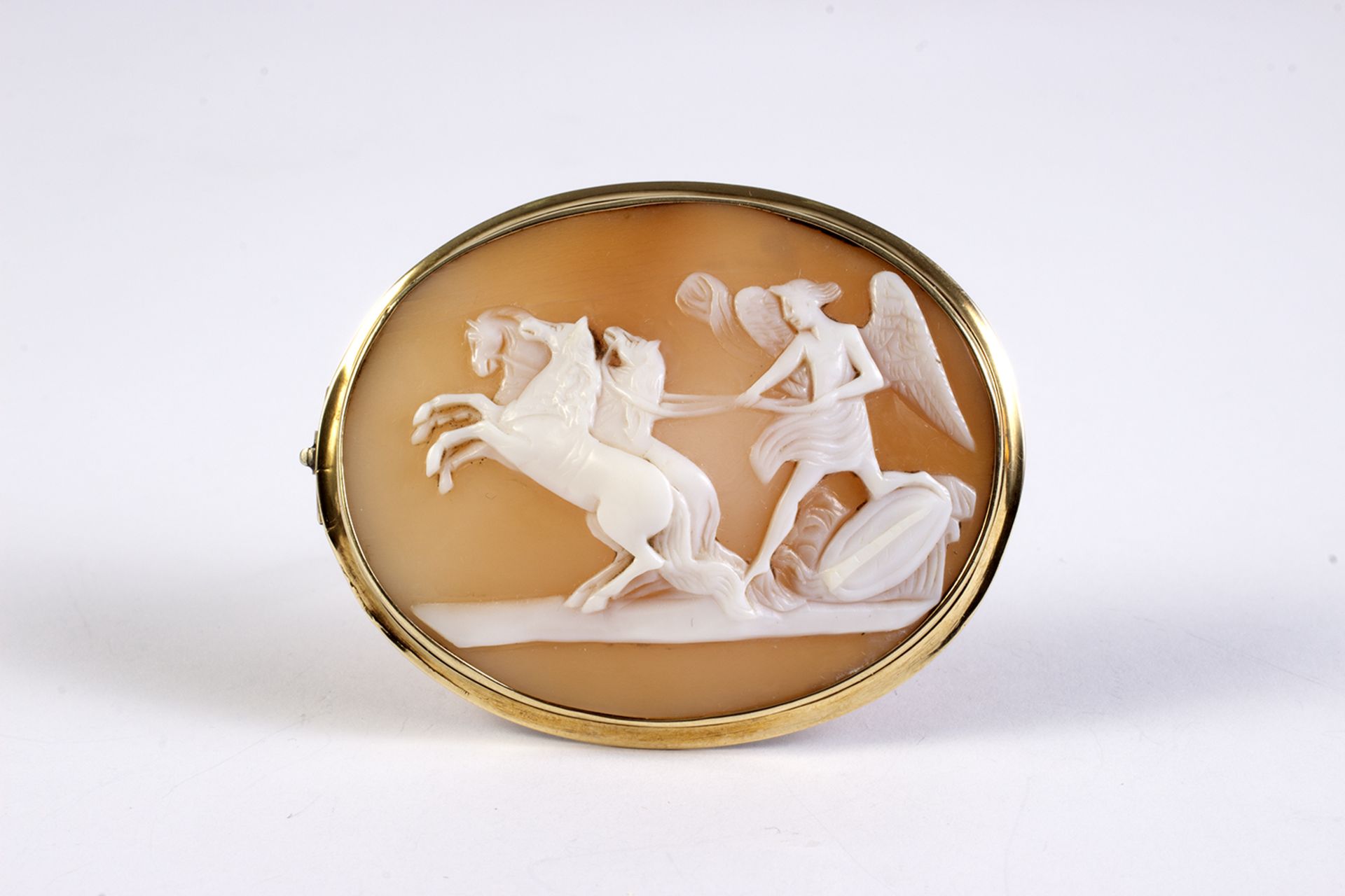 Broche camafeo en oro con representación de Cupido con caballos.