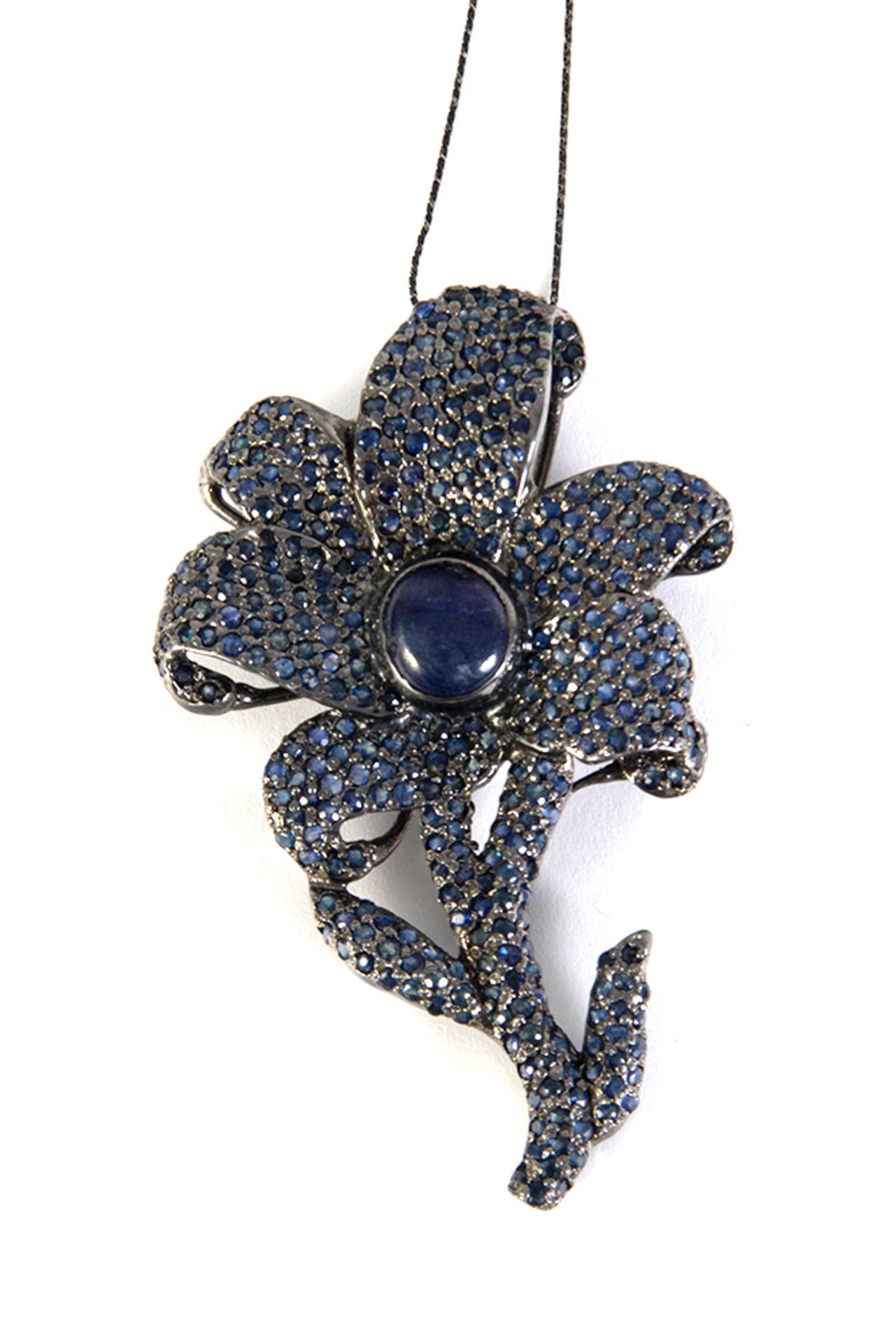 Silver flower pendant and blue sapphires, cabochon and round cut.