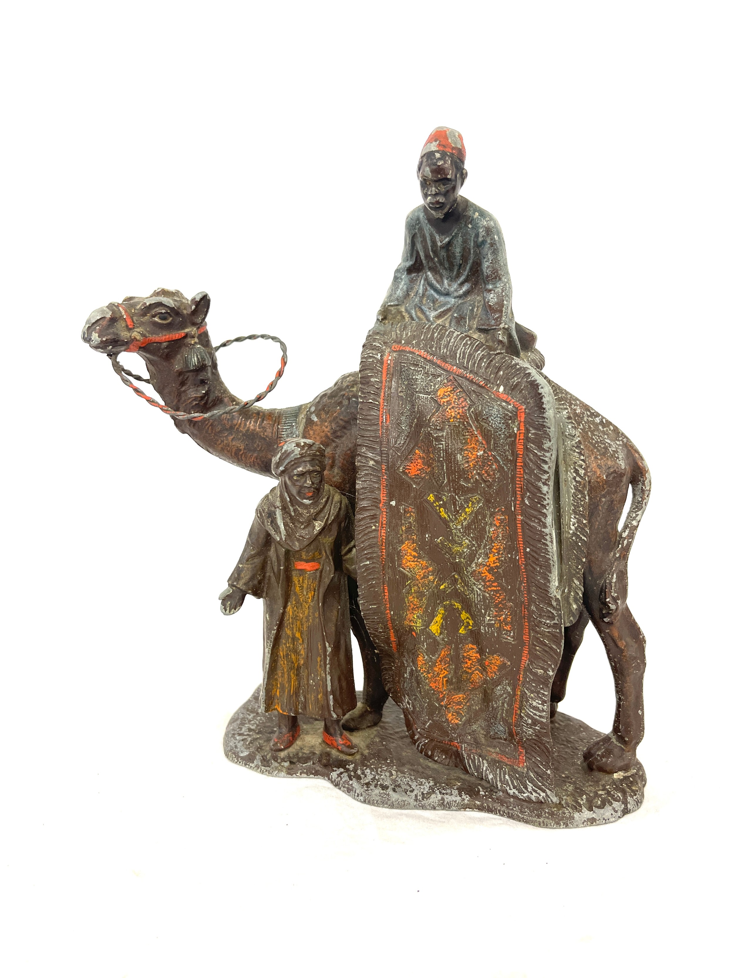 Metal ornament depicting a camel, men and rug