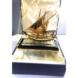 Boxed gold gilt model of a ship on glass and wood base ship measures approx 26cm wide height 24cm