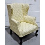 A modern wing back arm chair, with ball & claw feet and cream flowered upholstery.