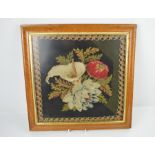 A 19th century needlework picture depicting poppies and tulips in a maple frame.
