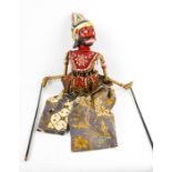 An Indonesian hand painted wooden puppet, with embroidered clothing and silk screen fabric.