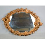 An oval gold painted plasterwork mirror, 67 by 48cm.