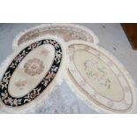 Three modern oval Chinese wool style rugs, one depicting cranes and calligraphy marks 152cm x 90cm