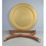 A Middle Eastern brass table top, on a wooden folding base, 71cm diameter.