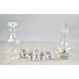 A cut glass decanter together with a 1950s glass decanter set, decorated with blue flowers.