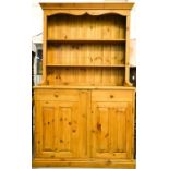 A pine dresser and rack, the enclosed having two shelves above two cupboards and single drawer,