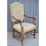 An 18th century walnut armchair, with tapestry back and seat, the arms carved with decoration.