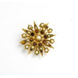 A gold (tested as), seed pearl and garnet starburst brooch, 4.6g.