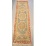 A Turkish Kayseria runner with blue and red ground and three large oval motifs to the centre,