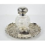 A silver dressing table tray and glass perfume bottle, the tray embossed with scrollwork and