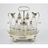 A George III silver and glass condiment set, with seven bottles, of boat form, raised on scroll