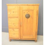 A pine cabinet with three short drawers beside a cupboard door.