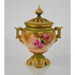 A Royal Worcester vase and cover, with twin handles painted with roses, and raised on four scroll