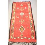 A Moroccan red ground runner, depicting camels and diamond motifs, 5ft6 by 2ft8ins.