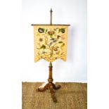 A 19th century pole screen with brass pole on walnut tripod, raising a crewel work panel depicting