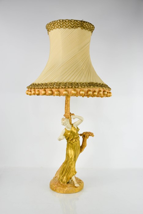 A Royal Worcester table lamp in the form of a classical lady in gilded robes, standing beside a