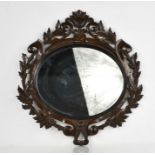 A 19th century carved oval wood mirror, with decoratively carved blackforest type frame depicting