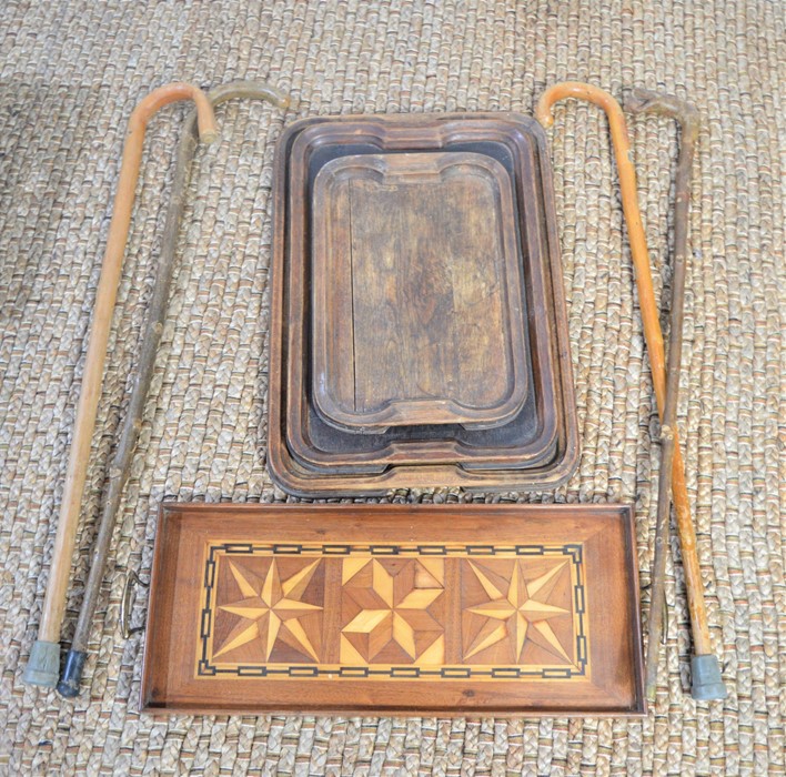 A group of 19th century wooden serving trays together with a quantity of walking sticks.