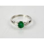 An 18ct white gold, emerald and diamond three stone ring, the emerald 0.8ct, the diamonds