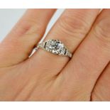 A fine platinum Art Deco diamond solitaire ring, the old cut diamond flanked by diamonds to the