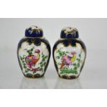 A pair of 18th century Worcester canisters with covers decorated with exotic birds, on a cobalt blue